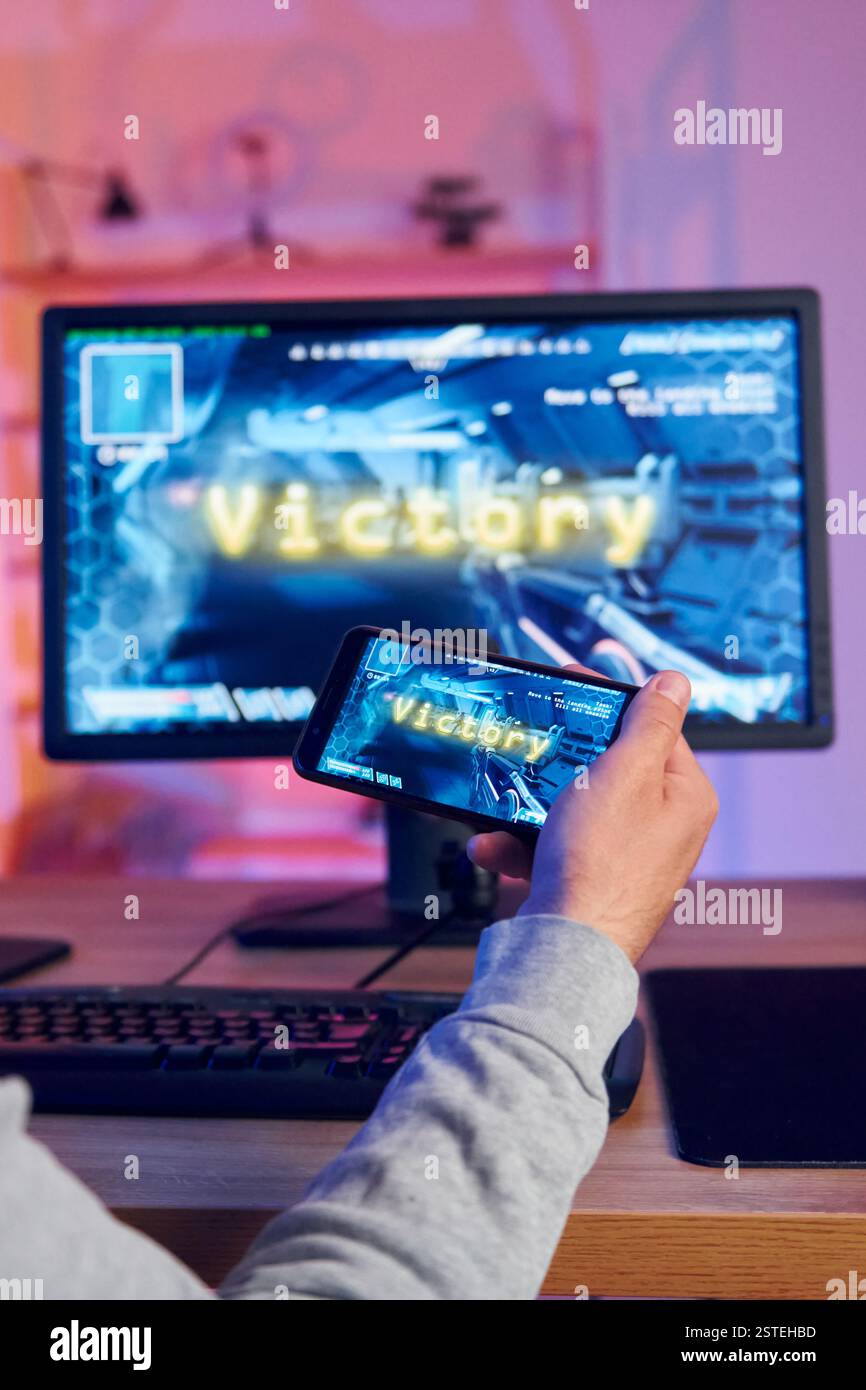 Sieg, glücklicher Mann, der feiert. Online-Streamer, der FPS-Shooter zu Hause spielt. Stockfoto