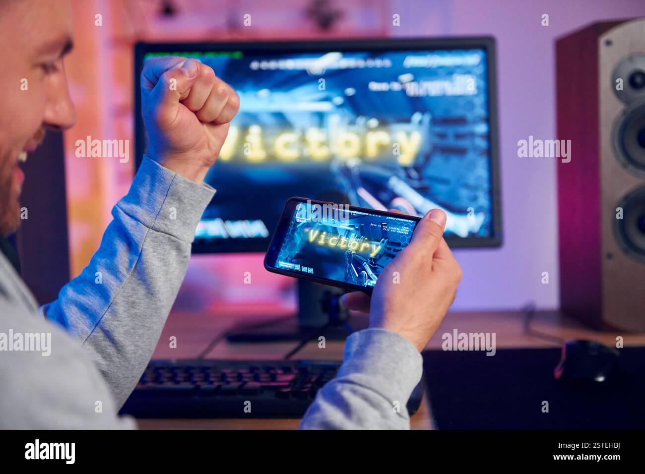 Sieg, glücklicher Mann, der feiert. Online-Streamer, der FPS-Shooter zu Hause spielt. Stockfoto