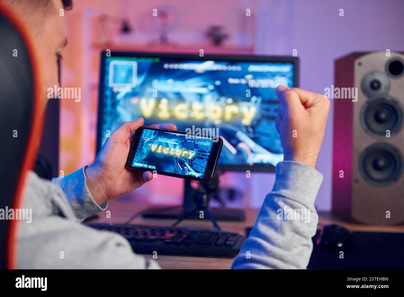 Sieg, glücklicher Mann, der feiert. Online-Streamer, der FPS-Shooter zu Hause spielt. Stockfoto