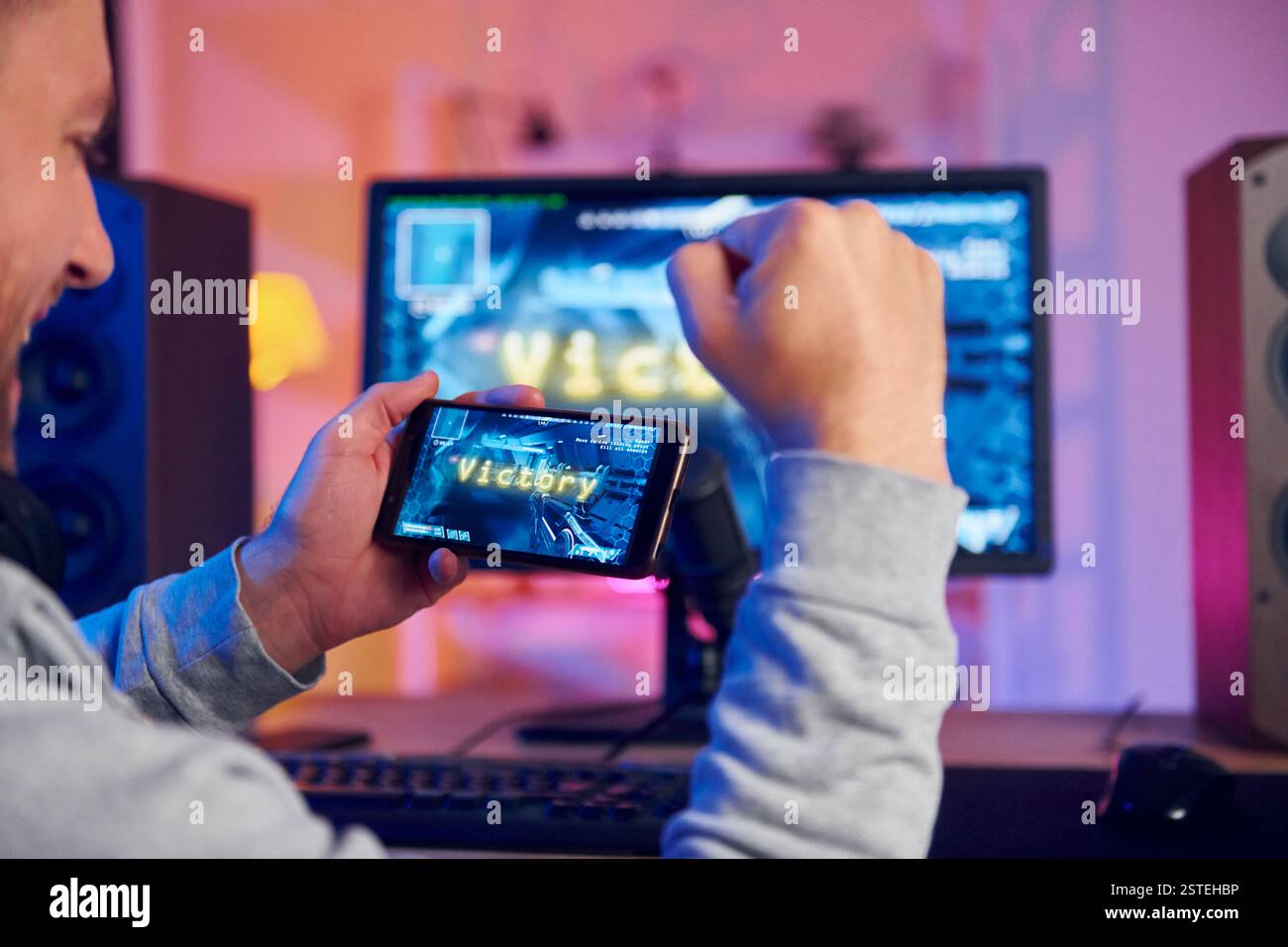 Sieg, glücklicher Mann, der feiert. Online-Streamer, der FPS-Shooter zu Hause spielt. Stockfoto