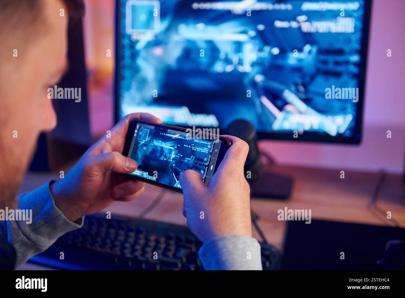 Anzeige des Monitors und des Smartphones. Online-Streamer, der FPS-Shooter zu Hause spielt. Stockfoto