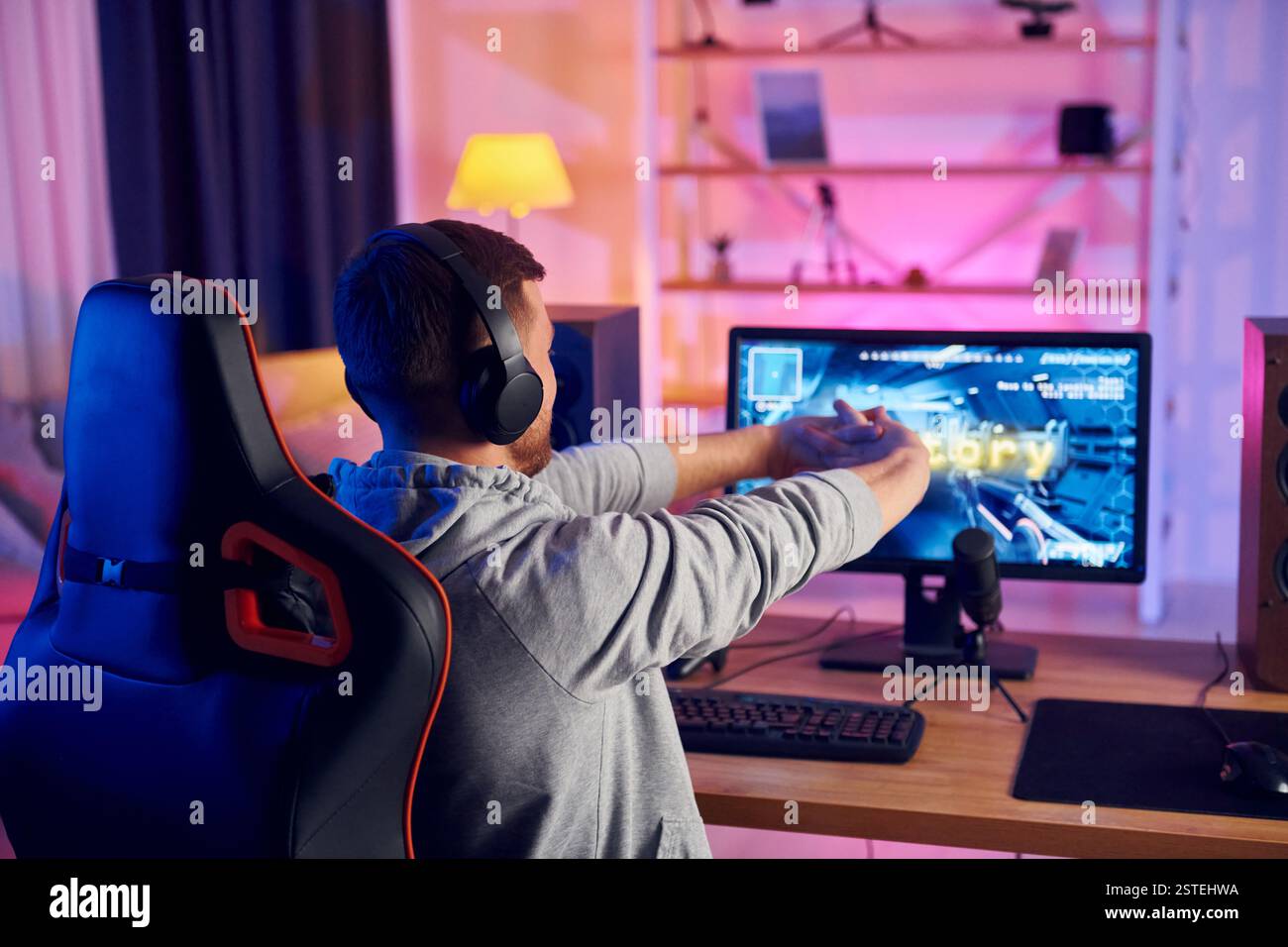 Rückansicht. Online-Streamer, der FPS-Shooter zu Hause spielt. Stockfoto