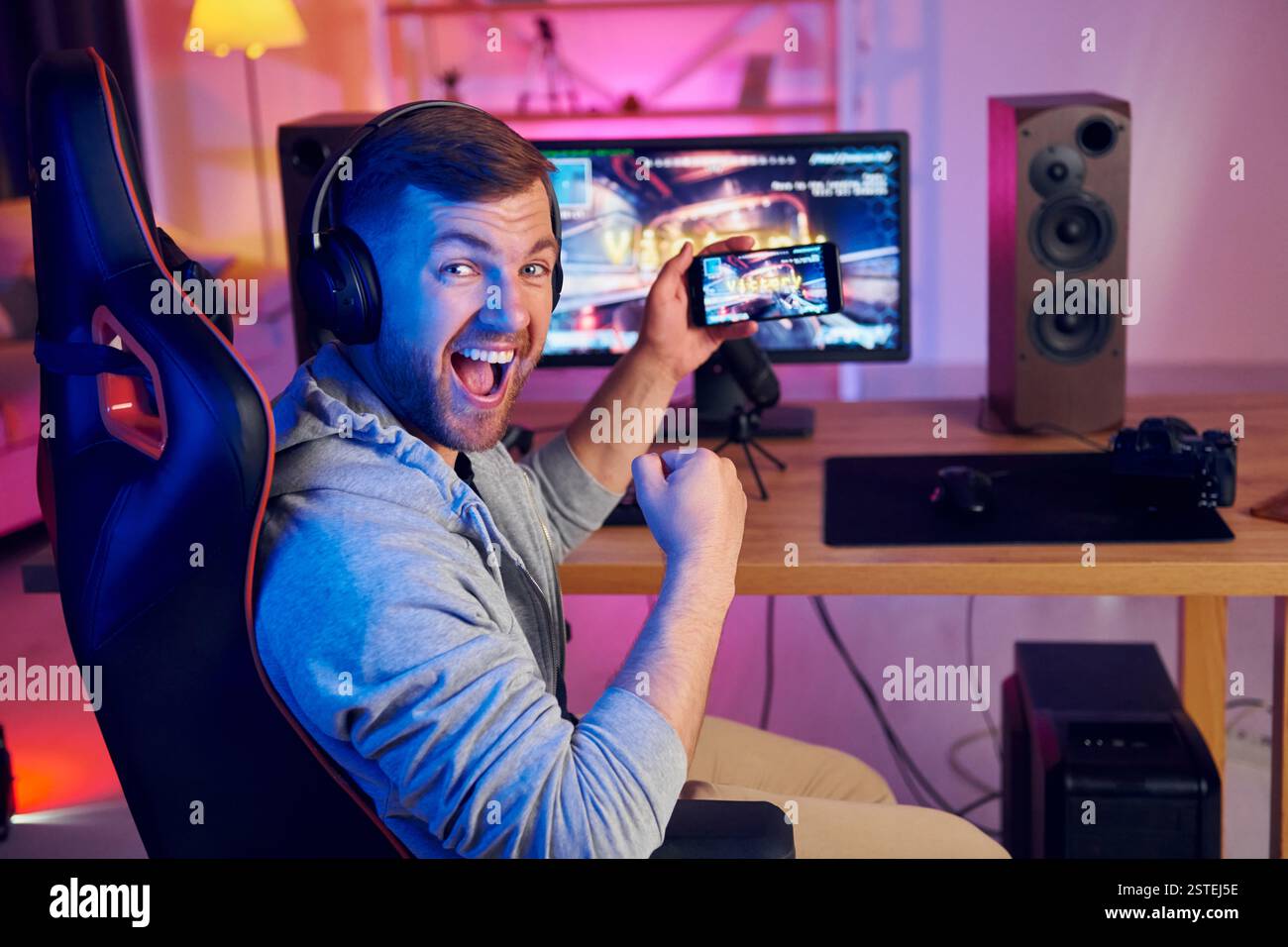 Zeigt den Sieg, der auf dem Bildschirm des Displays und des Telefons angezeigt wird. Online-Streamer, der FPS-Shooter zu Hause spielt. Stockfoto