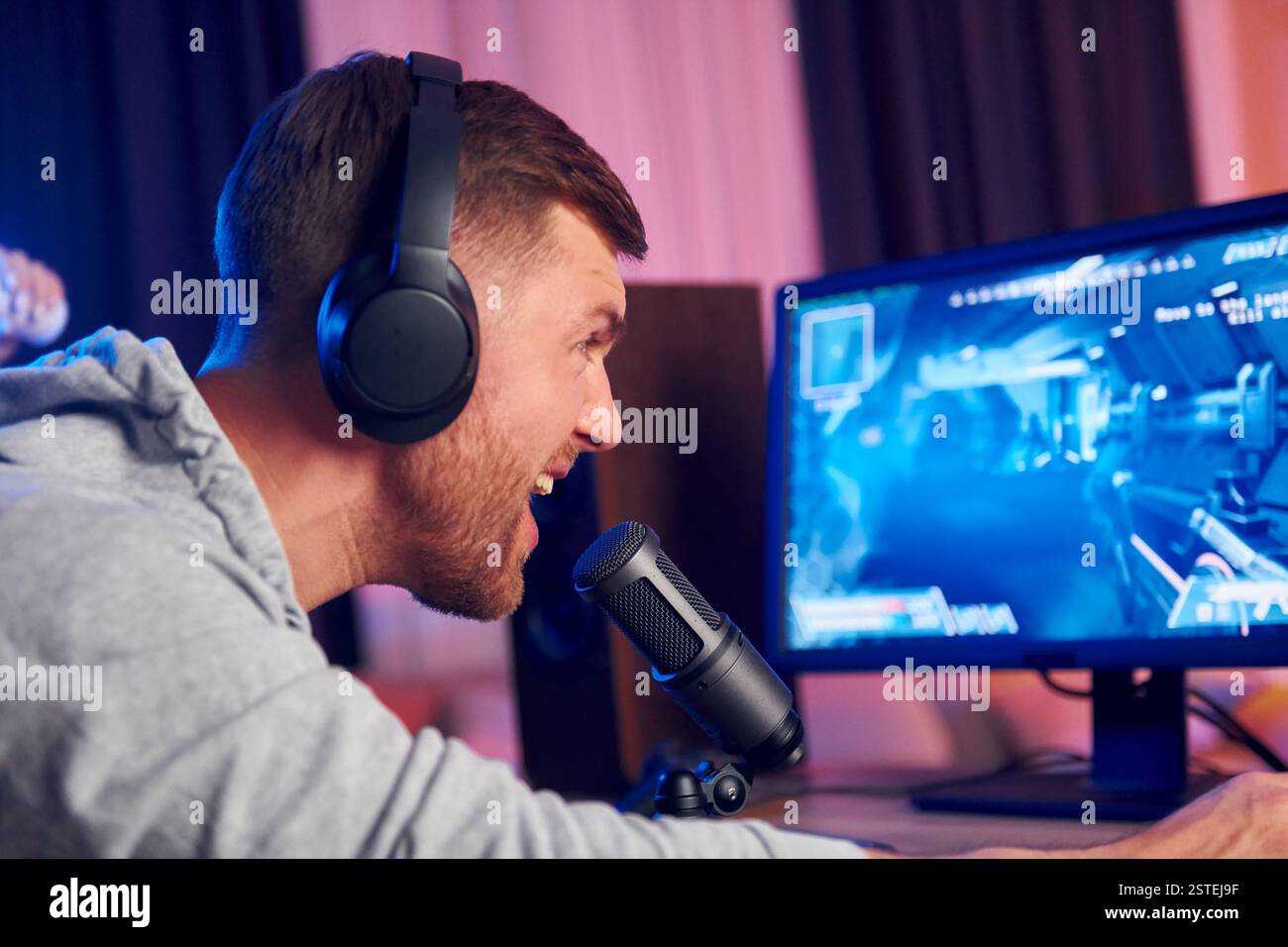 Sprechen Sie mit dem Publikum über das Mikrofon. Online-Streamer, der FPS-Shooter zu Hause spielt. Stockfoto