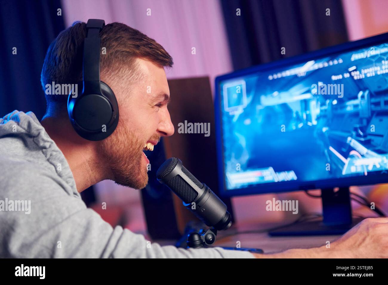 Sprechen Sie mit dem Publikum über das Mikrofon. Online-Streamer, der FPS-Shooter zu Hause spielt. Stockfoto