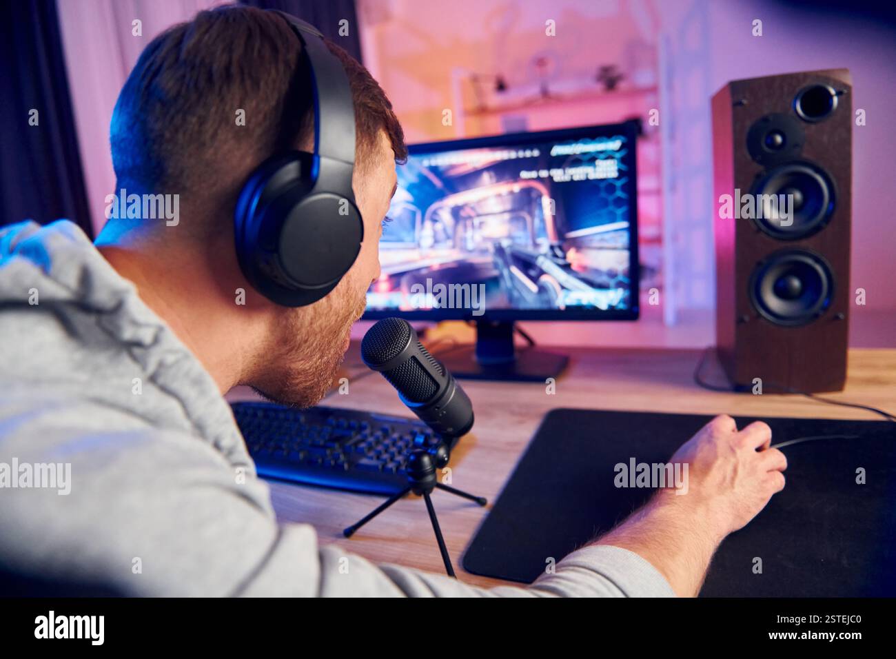 Sprechen Sie mit dem Publikum über das Mikrofon. Online-Streamer, der FPS-Shooter zu Hause spielt. Stockfoto