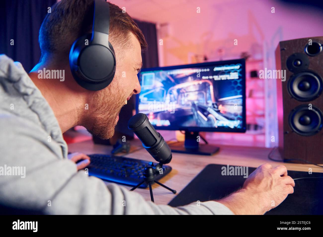 Sprechen Sie mit dem Publikum über das Mikrofon. Online-Streamer, der FPS-Shooter zu Hause spielt. Stockfoto