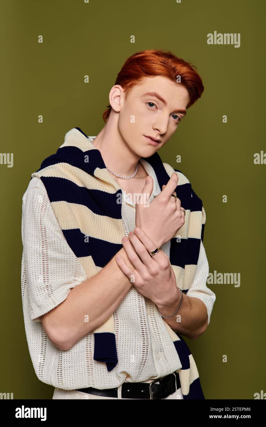 Junger Mann mit auffälligen Details zeigt seine Emotionen vor einem strukturierten grünen Hintergrund. Stockfoto