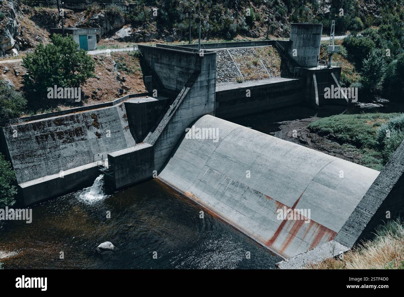 Ein Betondamm entlang des Passadicos do Mondego, der die Wasserwirtschaft mit der umliegenden zerklüfteten Landschaft verbindet Stockfoto