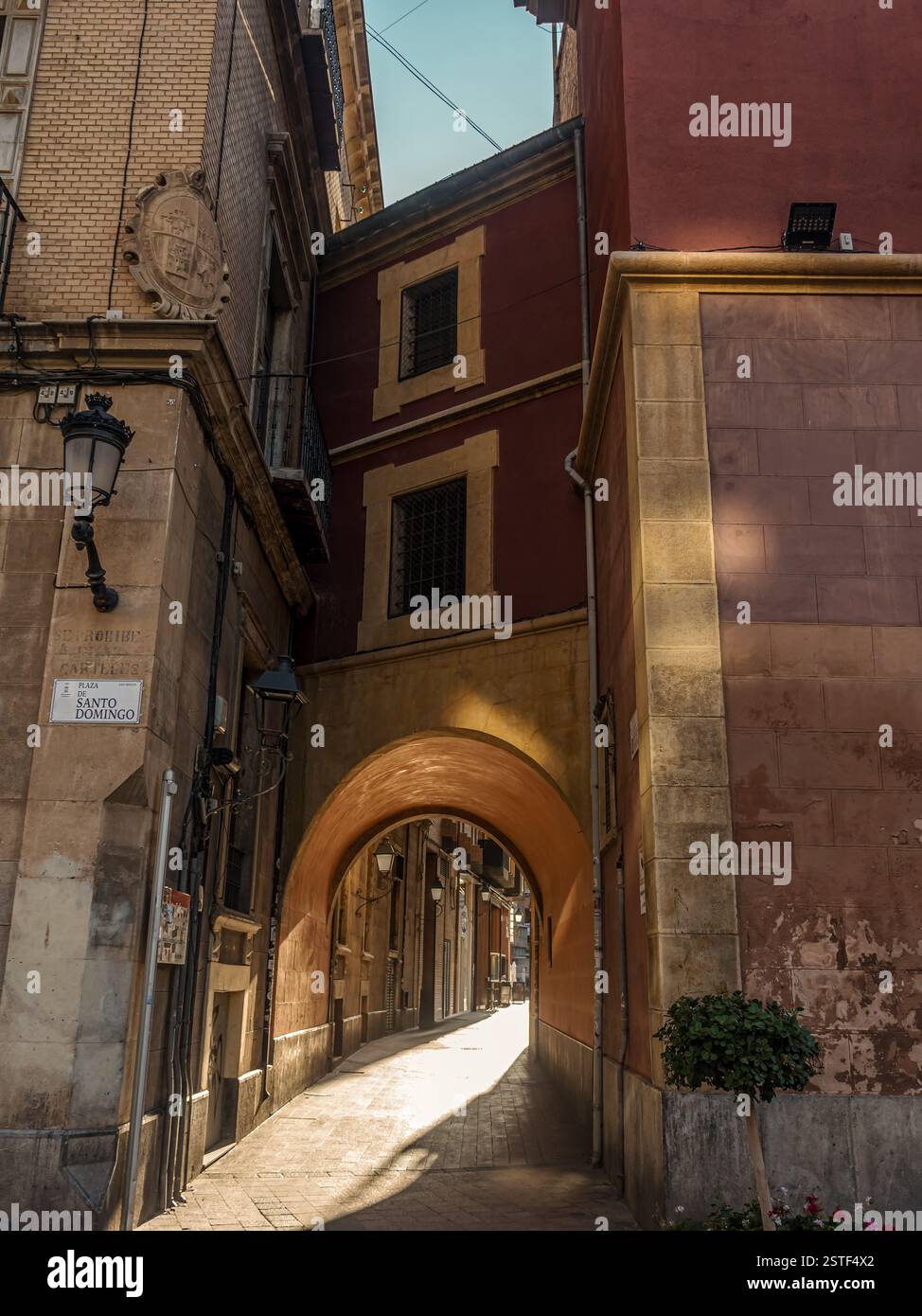 Eine malerische Szene eines Bogens in einer historischen europäischen Stadtstraße, wunderschön beleuchtet von natürlichem Sonnenlicht, Murcia, Spanien Stockfoto