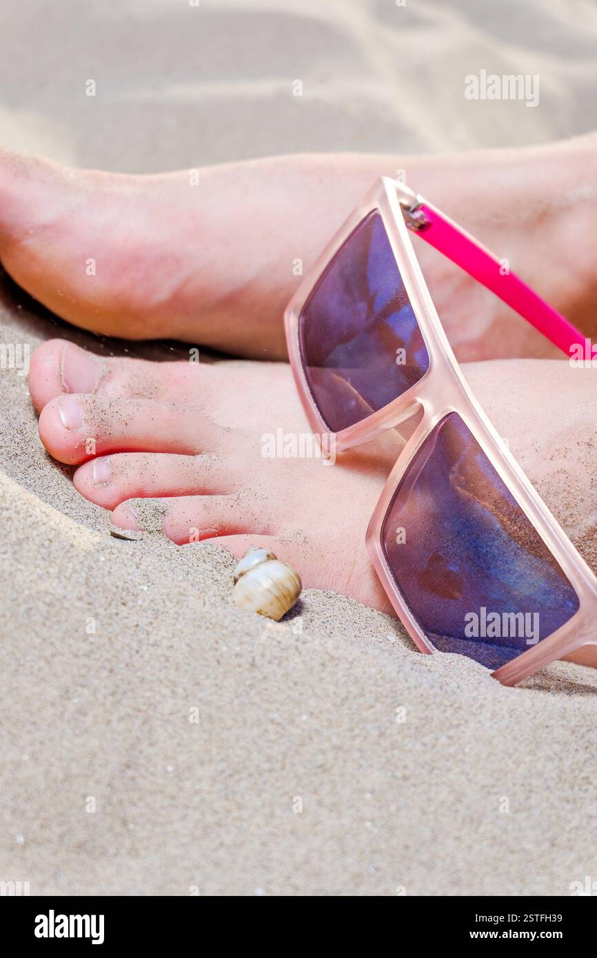 Junge Frauen Füße auf Sand mit lustigen Party Sonnenbrillen über Textfreiraum Stockfoto