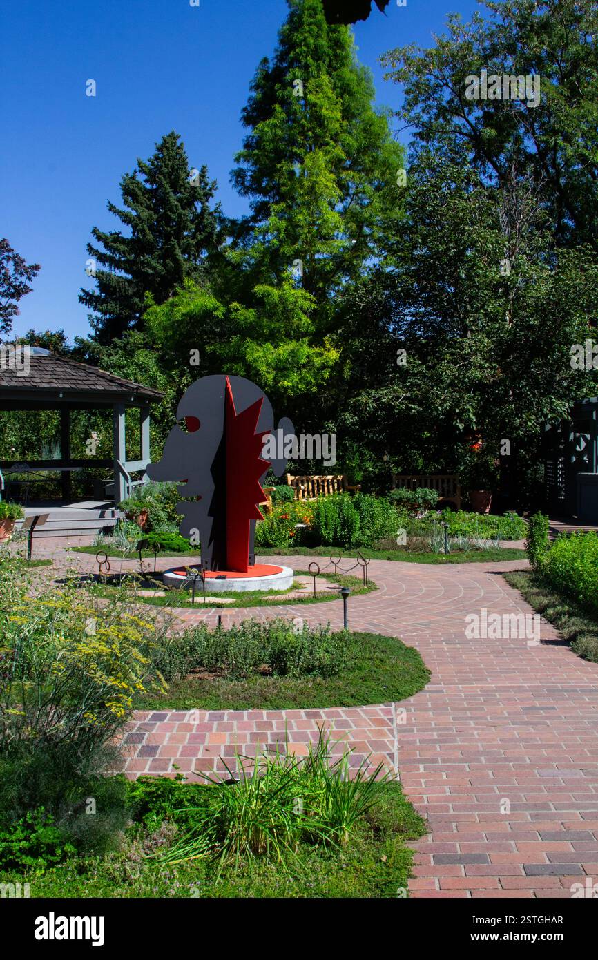 Eine auffällige rote Calder-Kopf- und Gesichtsskulptur steht im Kontrast zum umliegenden Grün des botanischen Gartens in Denver, Colorado. Stockfoto