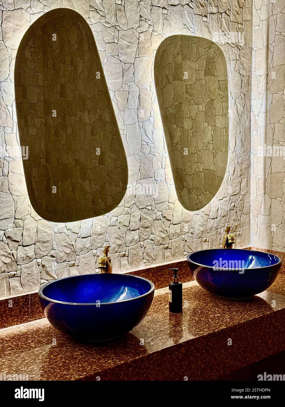 Modernes Badezimmer-Design mit blauen Keramikwaschbecken und hinterleuchteten Spiegeln elegantes Foto von zwei blauen Keramikwaschbecken mit goldenen Armaturen, die auf einem polierten s platziert sind Stockfoto