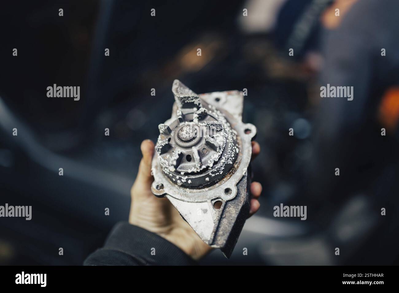 Person, die ein Autoteil aus Metall hält, konzentriert sich auf die Reparatur im Fahrzeug Stockfoto