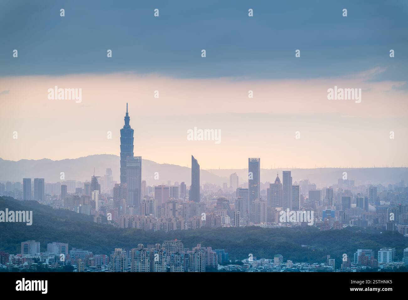 Blick auf das nebelige Stadtbild von Taipeh vom Dajian Mountain. Die Lichter der Stadt funkeln sanft im Dunst, während der Himmel darüber mit Delicat bemalt ist Stockfoto