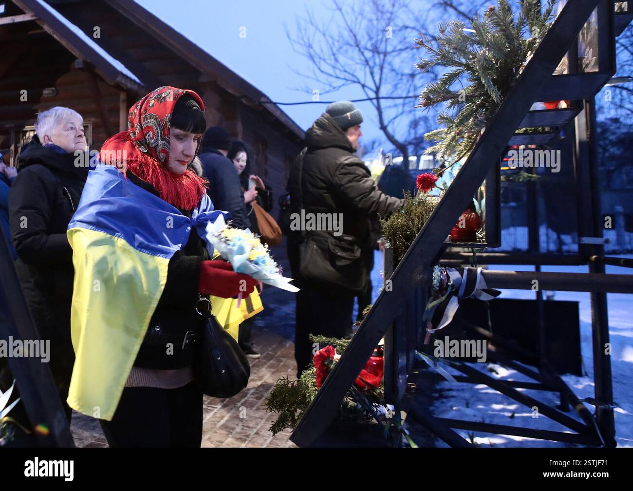 Nicht exklusiv: KIEW, UKRAINE - 18. FEBRUAR 2025 - Eine Frau wird während der Blumenzeremonie zum Gedenken an den Helden mit der Flagge der Ukraine gekleidet Stockfoto