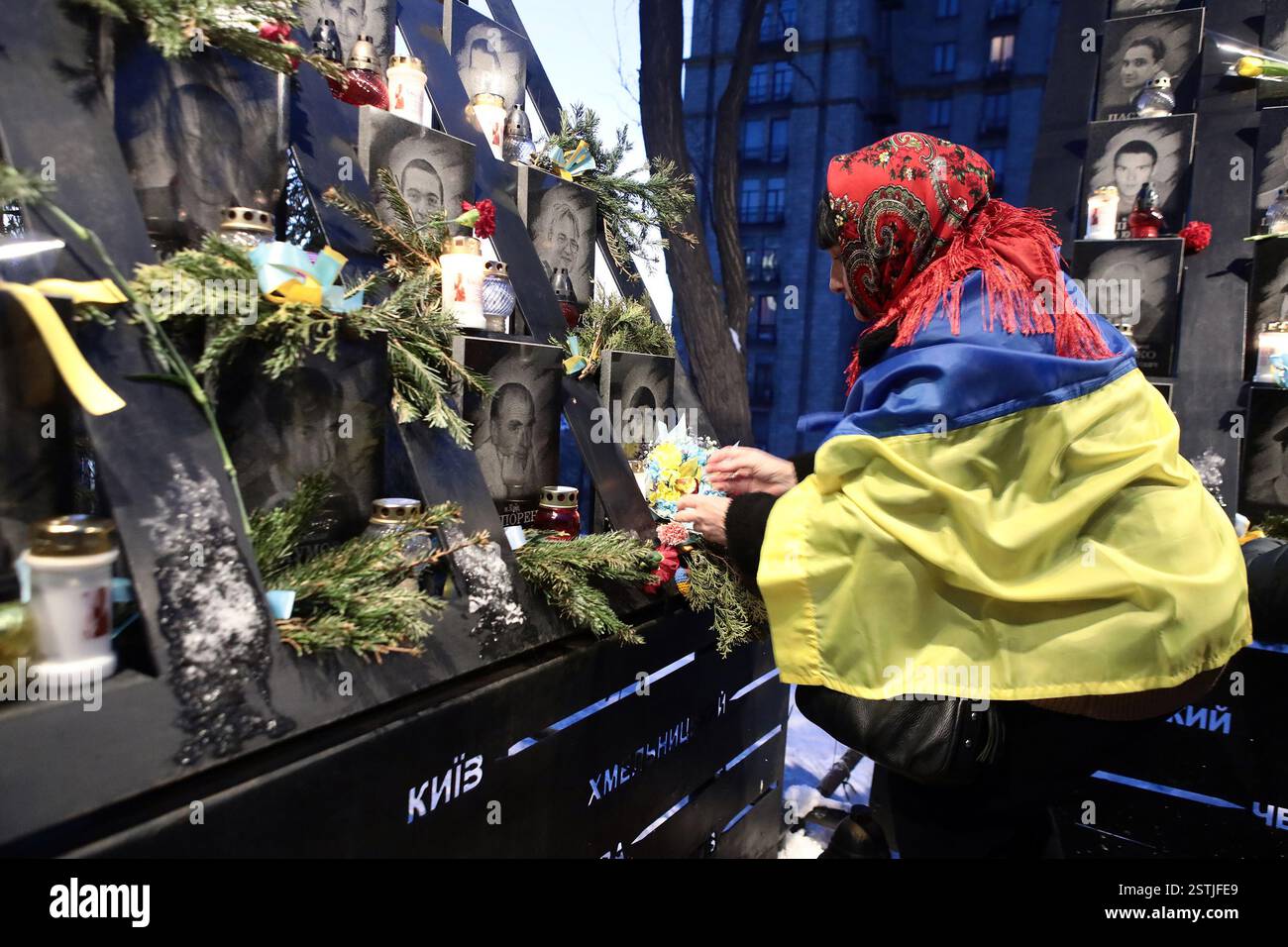 Nicht exklusiv: KIEW, UKRAINE - 18. FEBRUAR 2025 - Eine Frau wird während der Blumenzeremonie zum Gedenken an den Helden mit der Flagge der Ukraine gekleidet Stockfoto