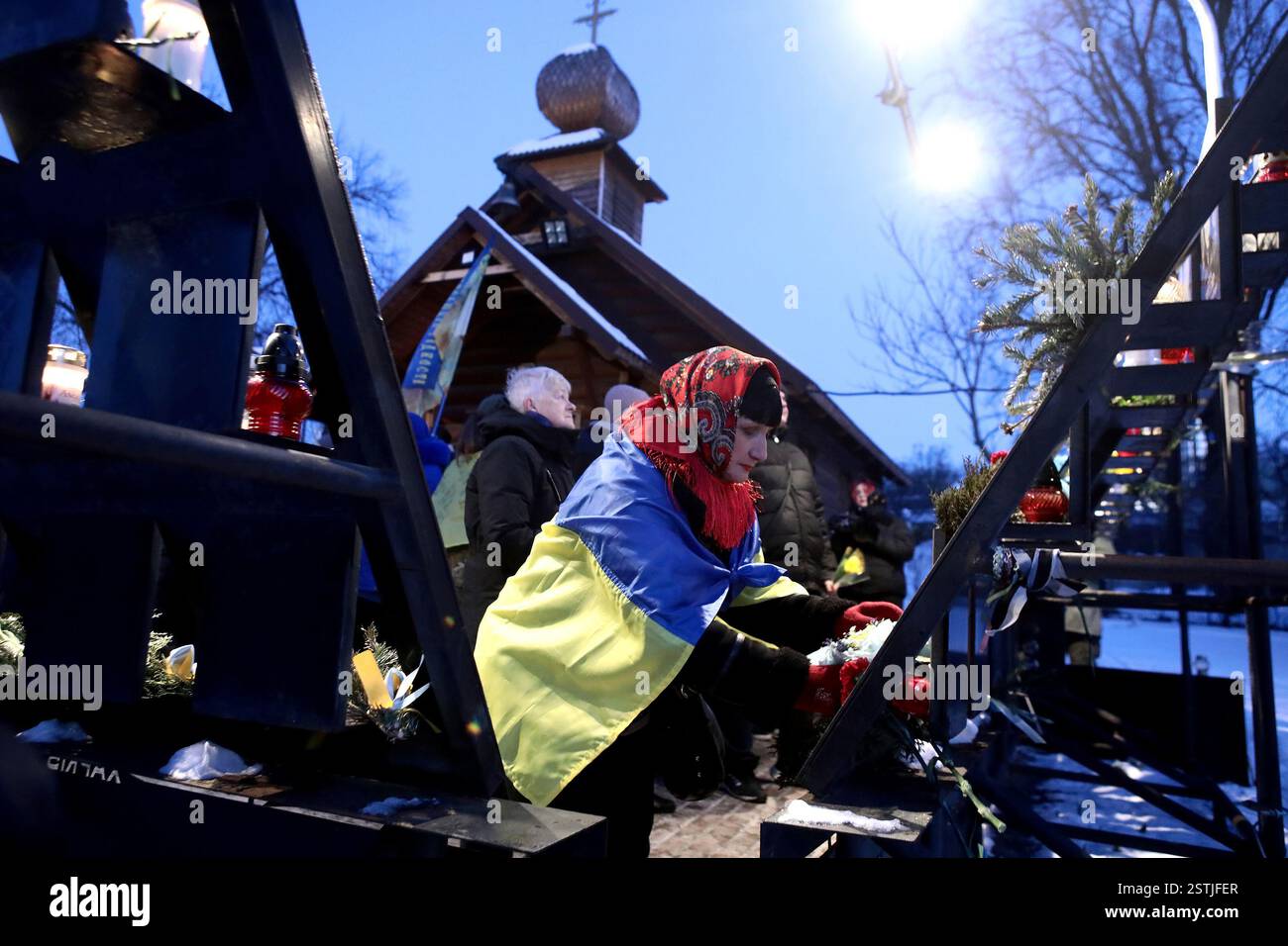 Nicht exklusiv: KIEW, UKRAINE - 18. FEBRUAR 2025 - Eine Frau wird während der Blumenzeremonie zum Gedenken an den Helden mit der Flagge der Ukraine gekleidet Stockfoto
