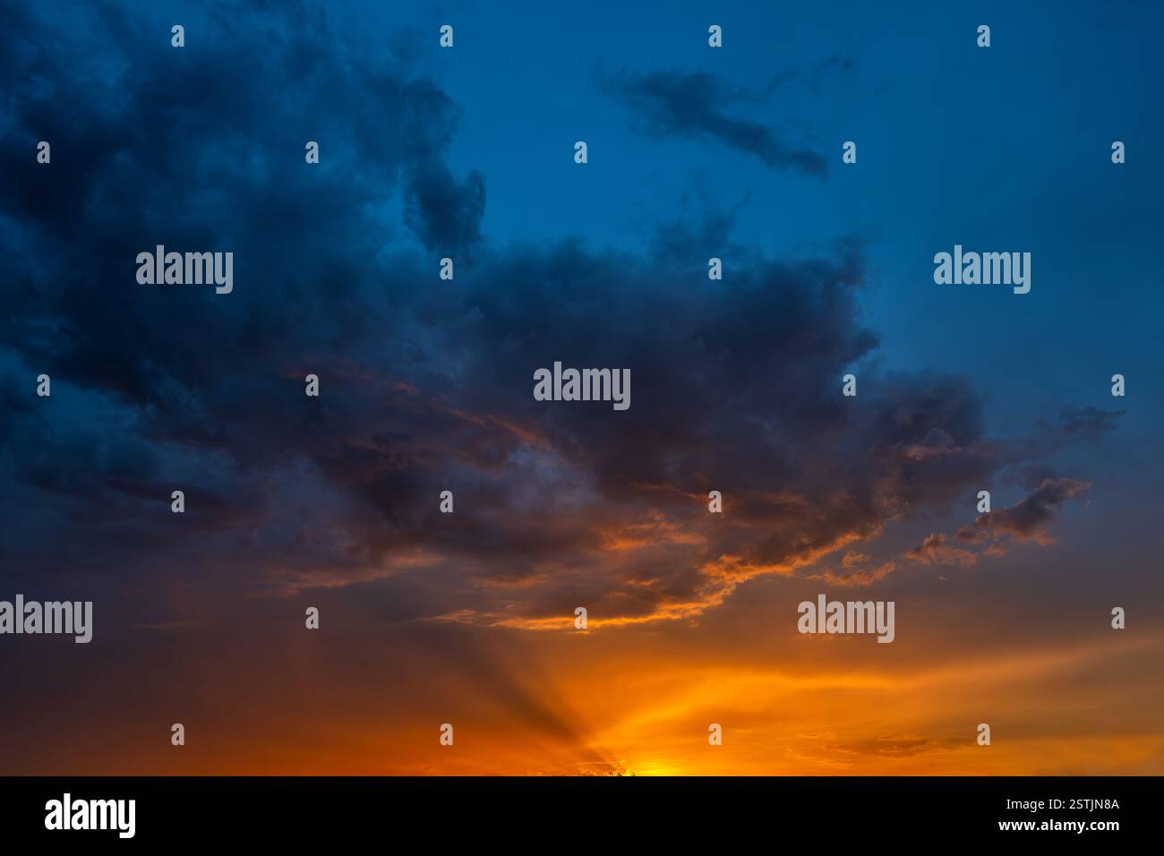Der Himmel geht in die Dämmerung über, wenn die Sonne untergeht, und malt den Horizont mit Orange- und Blautönen, während Wolken der Szene Tiefe und Textur verleihen. Stockfoto