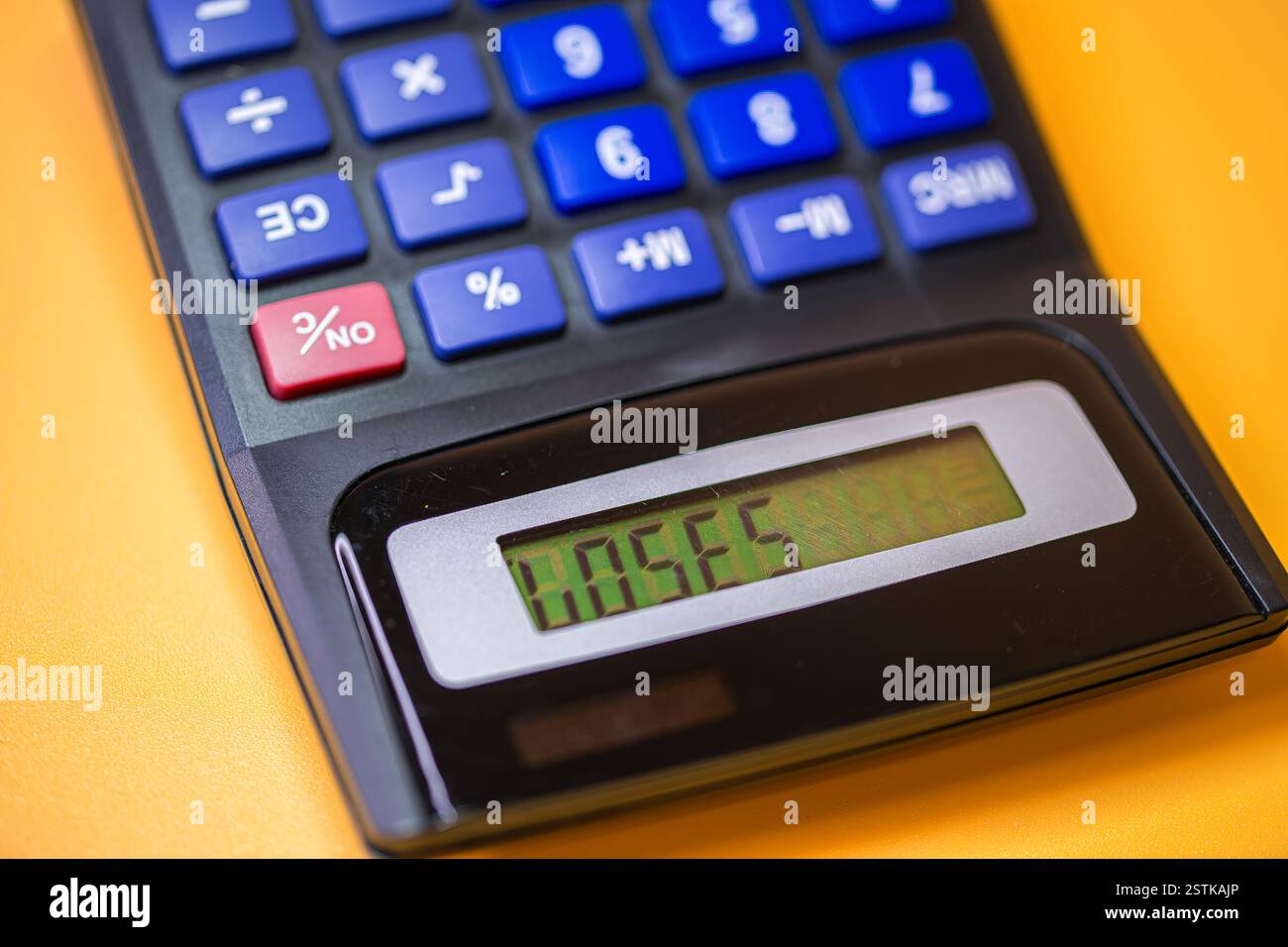 Taschenrechner mit einer digitalen Anzeige auf orangem Hintergrund, die finanzielle Entscheidungsfindung und Zufälligkeit symbolisiert, verliert Stockfoto