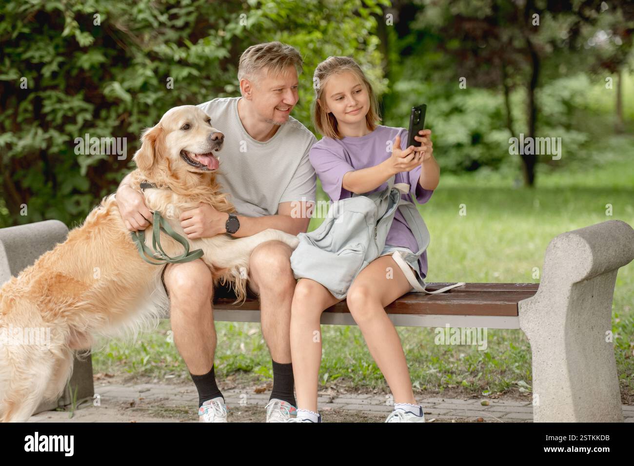 Vater und Tochter machen Ein lustiges Selfie mit Golden Retriever im Park Stockfoto