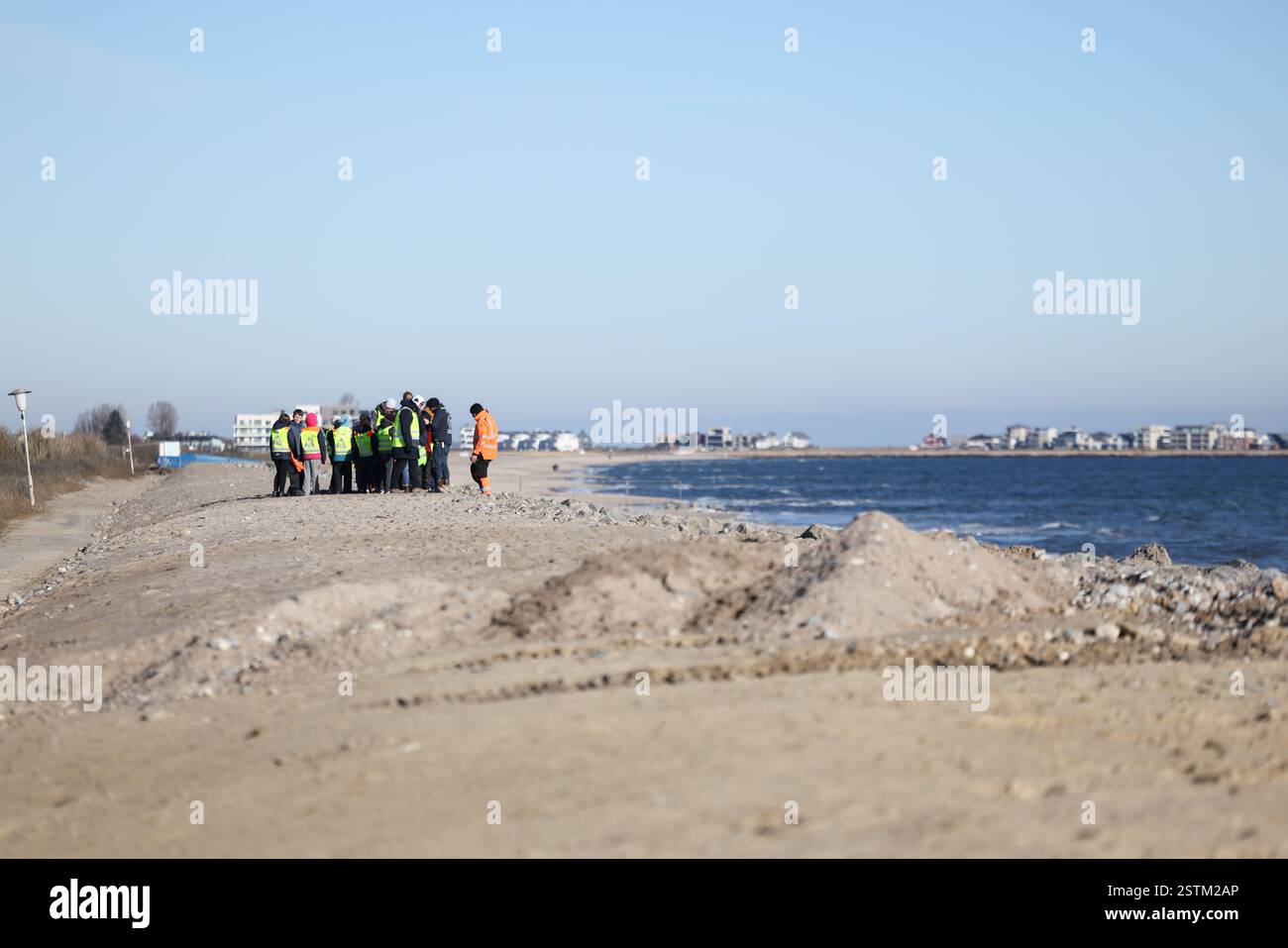 19. Februar 2025, Schleswig-Holstein, Schönhagen: Kinder der Grundschule Karby stehen auf einem Abschnitt des neuen Deiches auf der Baustelle auf einem Abschnitt des Deiches an der Ostsee bei Schönhagen während eines Lernausflugs. Die schwere Ostsee-Sturmflut im Oktober 2023 beschädigte den Deich bei Schönhagen schwer. Die Deichbaustelle sollte bis Ostern fertiggestellt sein. Foto: Christian Charisius/dpa Stockfoto