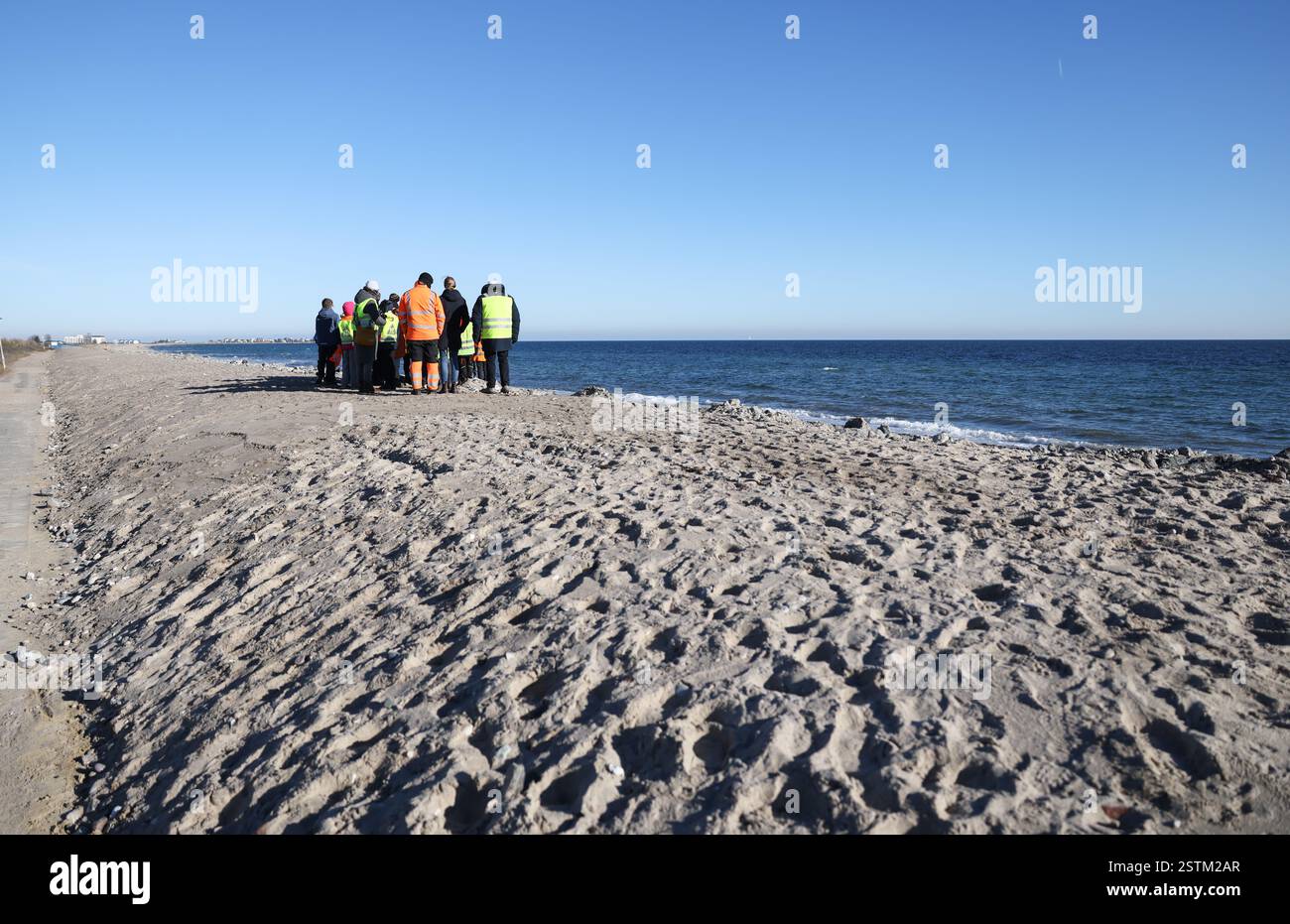 19. Februar 2025, Schleswig-Holstein, Schönhagen: Kinder der Grundschule Karby stehen auf einem Abschnitt des neuen Deiches auf der Baustelle auf einem Abschnitt des Deiches an der Ostsee bei Schönhagen während eines Lernausflugs. Die schwere Ostsee-Sturmflut im Oktober 2023 beschädigte den Deich bei Schönhagen schwer. Die Deichbaustelle sollte bis Ostern fertiggestellt sein. Foto: Christian Charisius/dpa Stockfoto