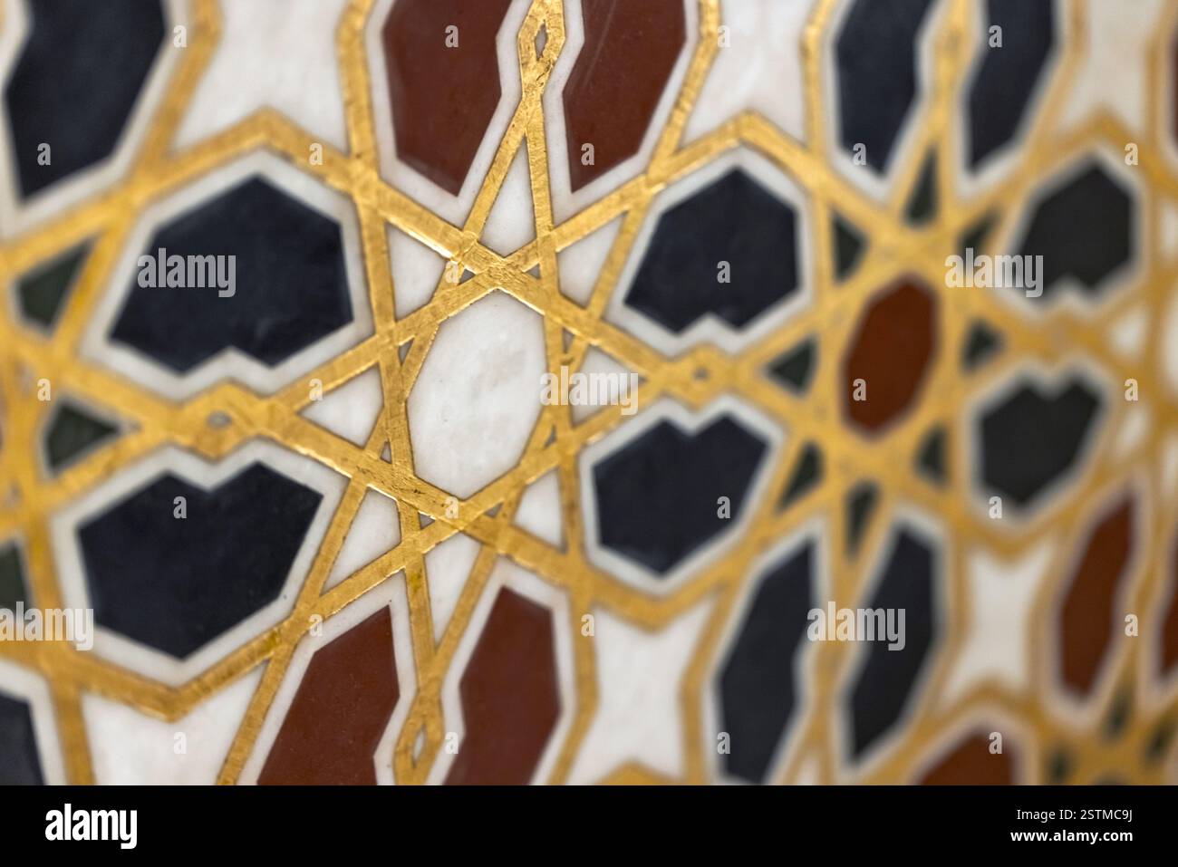 Goldene geometrische Muster auf Marmorfliesen zeigen komplizierte islamische Designkunst, die Symmetrie und Eleganz in einem wunderschönen Mosaik-Arrangement verbindet Stockfoto