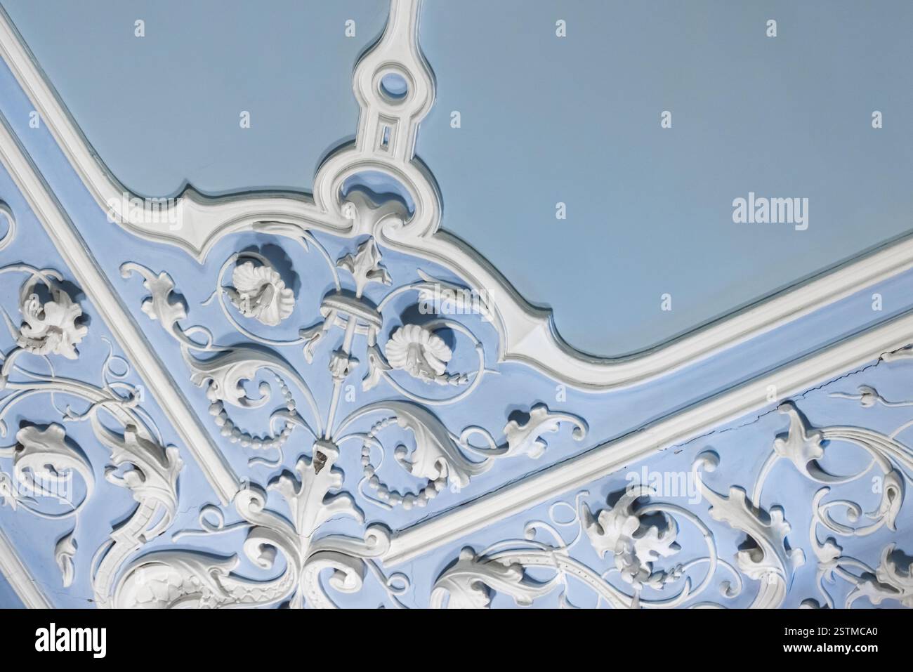 Kunstvolle weiße, skulpturale Putzleisten mit komplizierten Eckdesigns und Mustern vor einem hellblauen Deckenhintergrund, die klassisch sind Stockfoto Kunstvolle weiße, skulpturale Putzleisten mit komplizierten Eckdesigns und Mustern vor einem hellblauen Deckenhintergrund, die klassisch sind Stockfoto