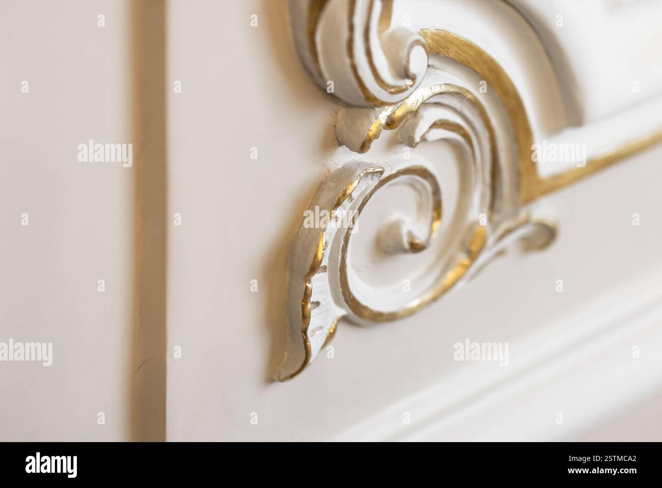 Nahaufnahme einer komplizierten goldenen Dekoration auf luxuriösem weißem Hintergrund, die dekorative Eleganz zeigt. Selektiver Weichfokus Stockfoto