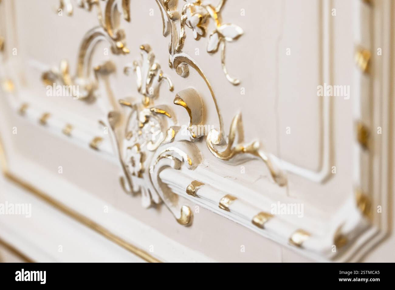 Detaillierte Ansicht einer komplexen goldenen Dekoration auf luxuriösem weißem Hintergrund, die dekorative Eleganz zeigt Stockfoto