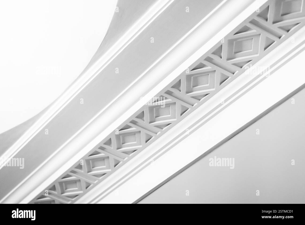 Ein Nahaufnahme eines weißen Deckengesims mit symmetrischem geometrischem Muster, das Eleganz, Minimalismus und detailgetreue Handwerkskunst zeigt Stockfoto Ein Nahaufnahme eines weißen Deckengesims mit symmetrischem geometrischem Muster, das Eleganz, Minimalismus und detailgetreue Handwerkskunst zeigt Stockfoto