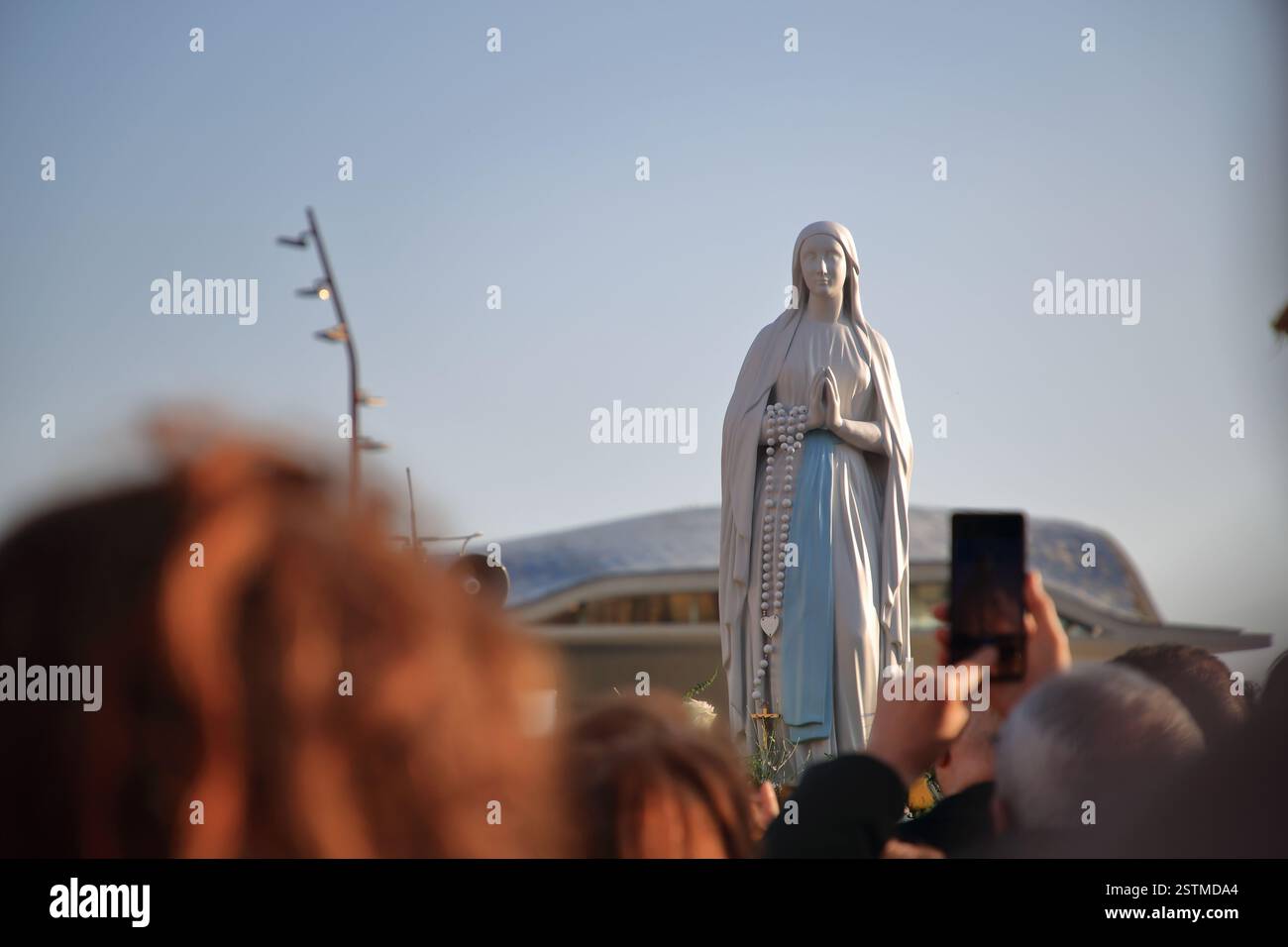 Die Statue unserer Lieben Frau von Lourdes kam mit dem Hubschrauber an und wird in einer Prozession durch die Straßen der Altstadt getragen. Stockfoto