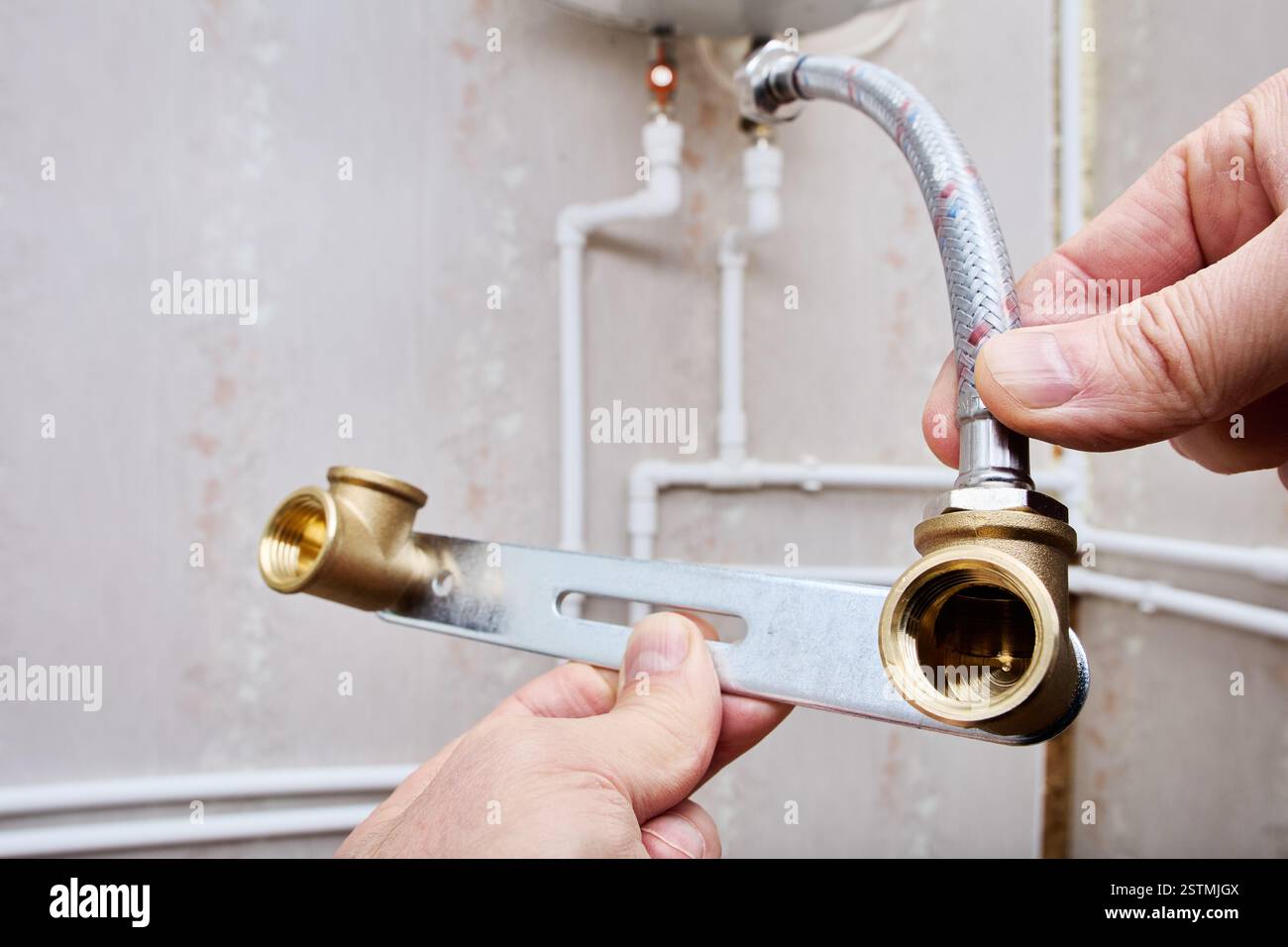 Flexibler Schlauch mit Edelstahlgeflecht und lockerer Mutter, Innengewinde mit Gummischeiben an beiden Enden, die mit Rohrleitungen verbunden sind. Stockfoto