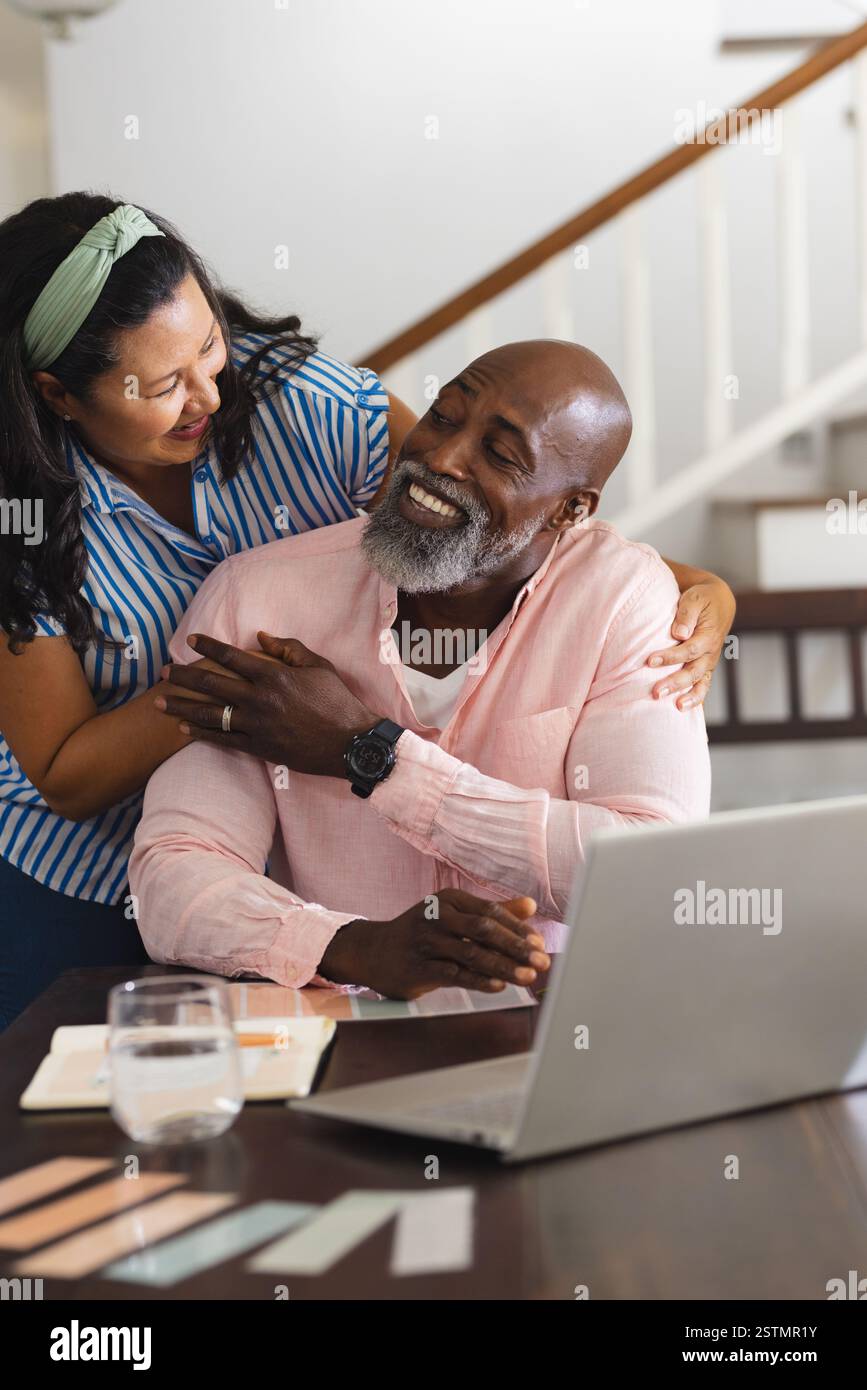 Afroamerikanisches Senior-Paar, das zu Hause mit einem Laptop lächelt und umgeht. Lifestyle, Technologie, Kommunikation, verschiedene Seniorenfreunde, Stockfoto