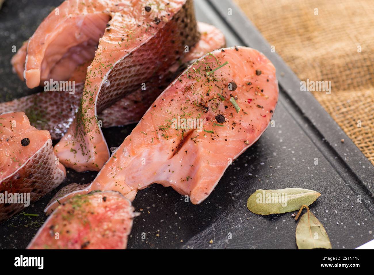 Rohe Stücke von rotem Fisch mit Gewürzen. Stockfoto