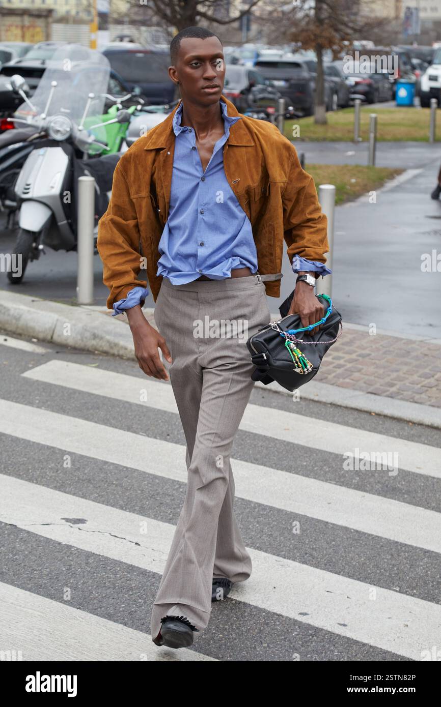 MAILAND, ITALIEN - 19. JANUAR 2025: Alioune Badara fällt mit brauner Wildlederjacke und Prada Tasche vor der Prada Fashion Show, Mailand Fashion Week Street Style Stockfoto