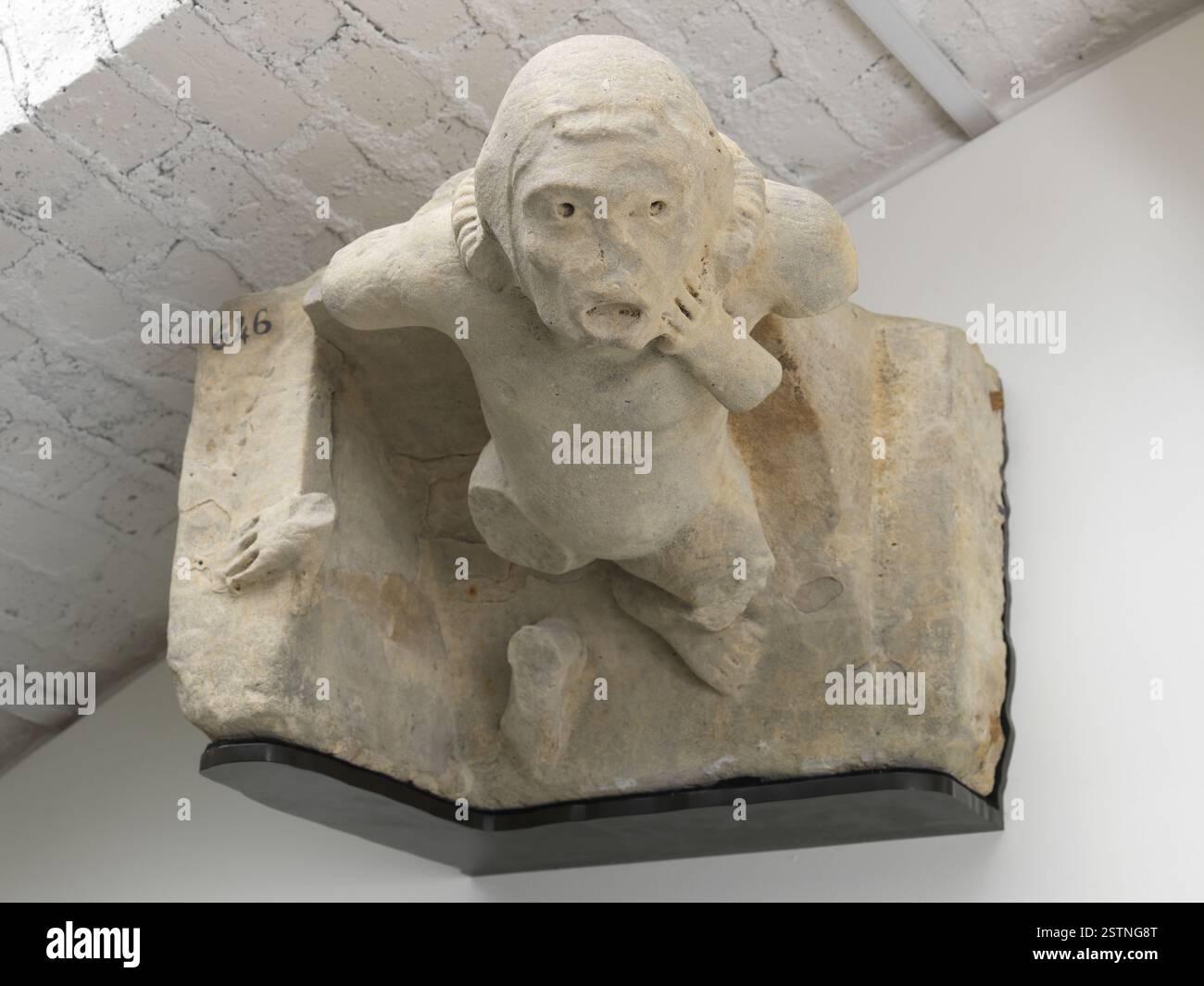 Eine mittelalterliche Skulptur, die Marmouset zeigt, einen Hofzwerg aus dem 13. Jahrhundert, der mit der Hand auf der Wange an eine Wand gelehnt ist. Dieses Stück bietet einen Einblick in das mittelalterliche Hofleben. Stockfoto