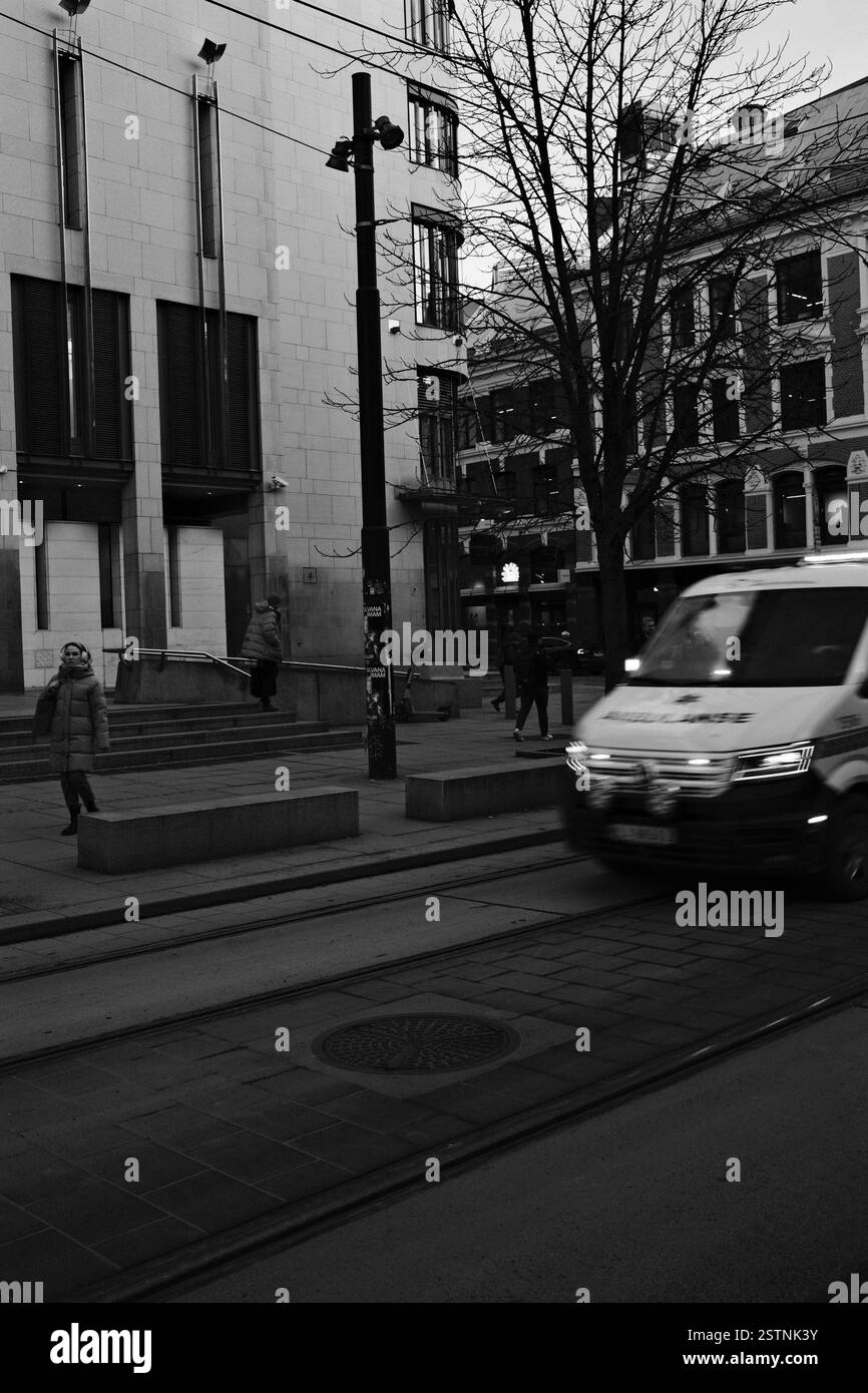Krankenwagen mit blinkenden Lichtern während eines Anrufs in der Nähe des Stadtzentrums in Oslo. Gerichtssaal und Gebäude im Hintergrund Stockfoto