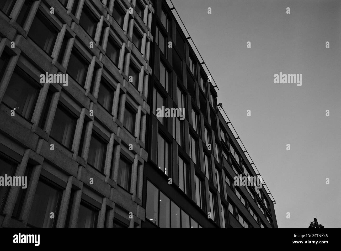 Das Bild zeigt ein modernes Gebäude mit einer einzigartigen Fassade mit geometrischen Linien und großen Glasfenstern, die sich vor dem Dämmerhimmel befinden Stockfoto