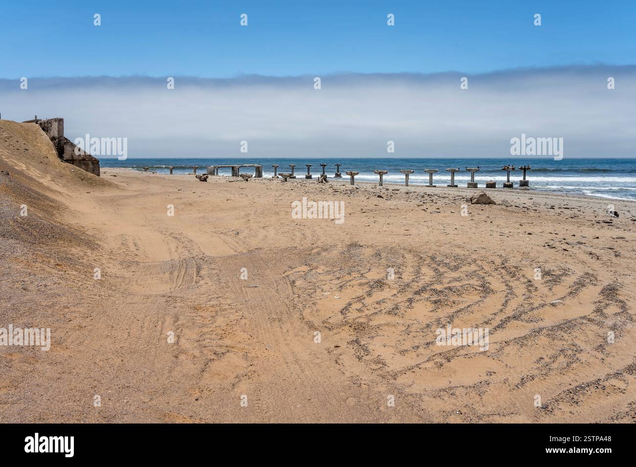 Landschaft mit heruntergekommenem Pier an der Küste des Ozeans, aufgenommen im hellen Licht des späten Frühlings an der alten Bergbaustelle von Toscanini, Skeleton Coast, Namibia, Afrika Stockfoto