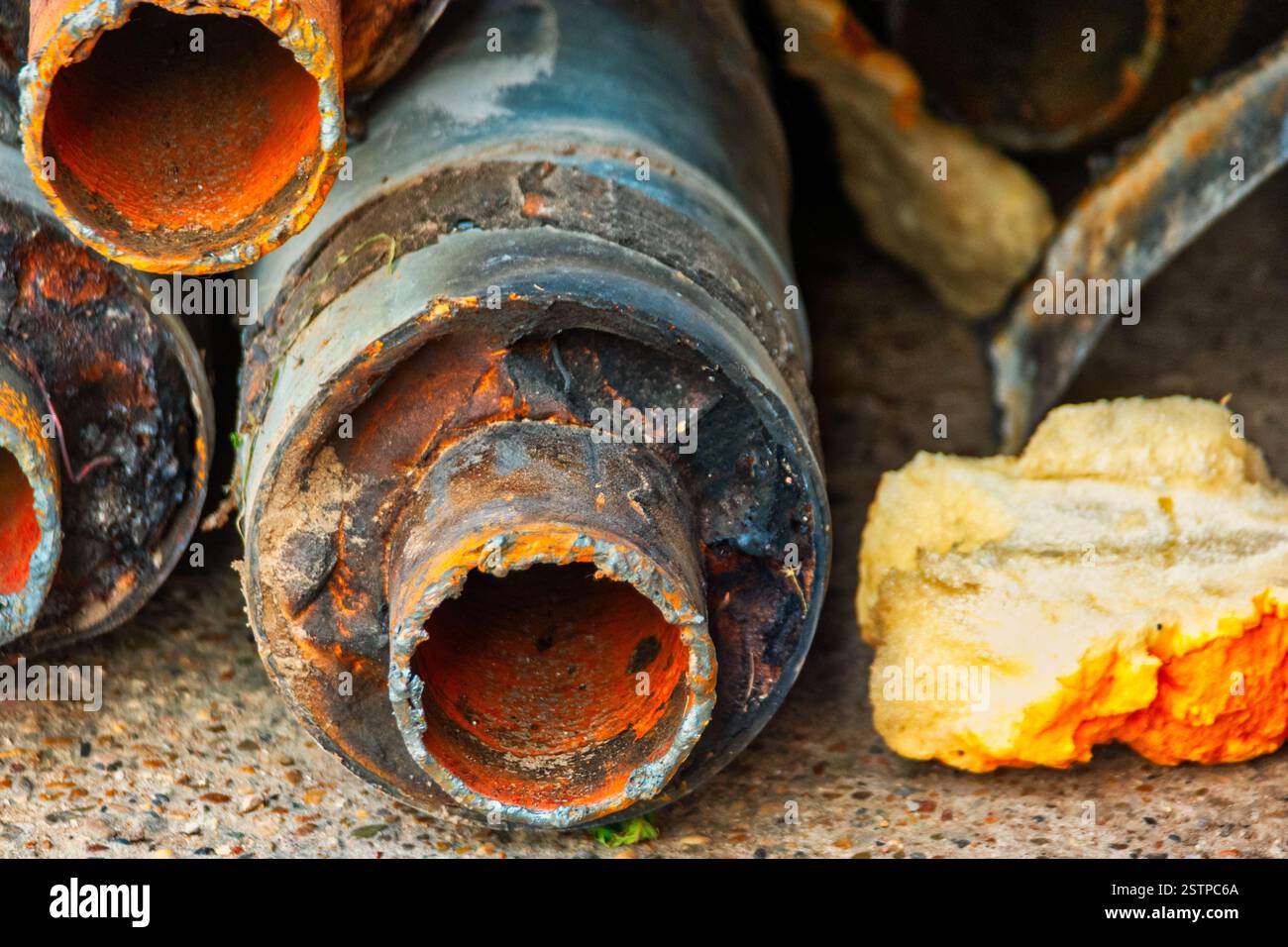 Enden verschlissener Warmwasserleitungen im Stapel in der Nähe der Wand Stockfoto
