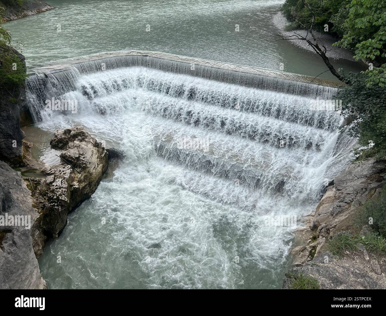 Ein Wasserfall, der über einen Betondamm fließt. - Smartphone-aufgenommenes Stockfoto