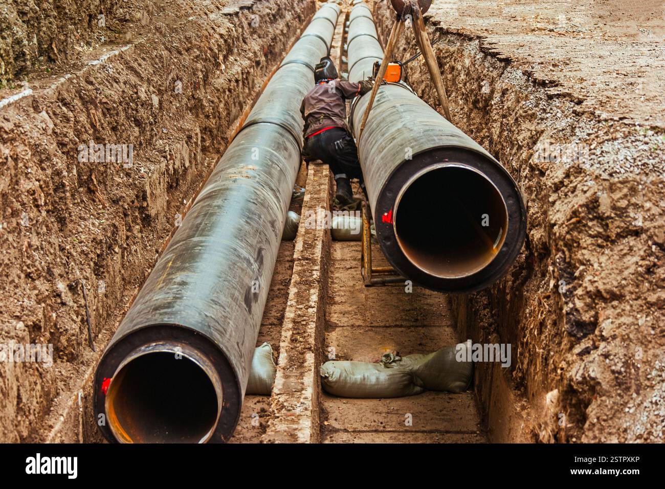 Ein Arbeiter verwendet eine kreisförmige Schweißmaschine an Heißwasserleitungen am Straßenrand Stockfoto