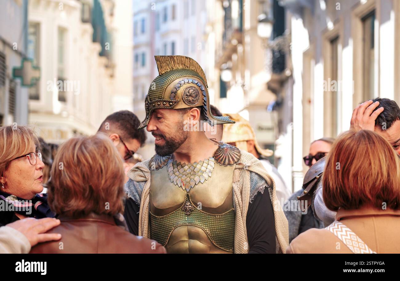Darsteller in römischer Rüstung bei urbanen Kulturveranstaltungen, interagiert mit fasziniertem Publikum auf der engen Straße der Stadt. Stockfoto