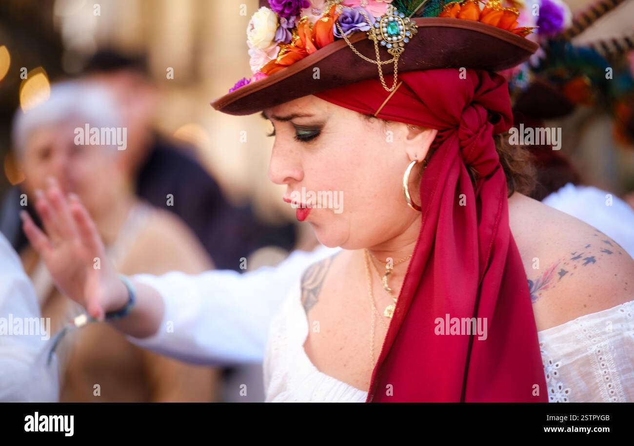 Das Bild zeigt eine Person, wahrscheinlich eine Frau, die einen farbenfrohen Kopfschmuck mit Blumen, einen roten Schal oder ein Bandana und einen goldenen Ohrring trägt, was darauf hindeutet, dass sie ist Stockfoto