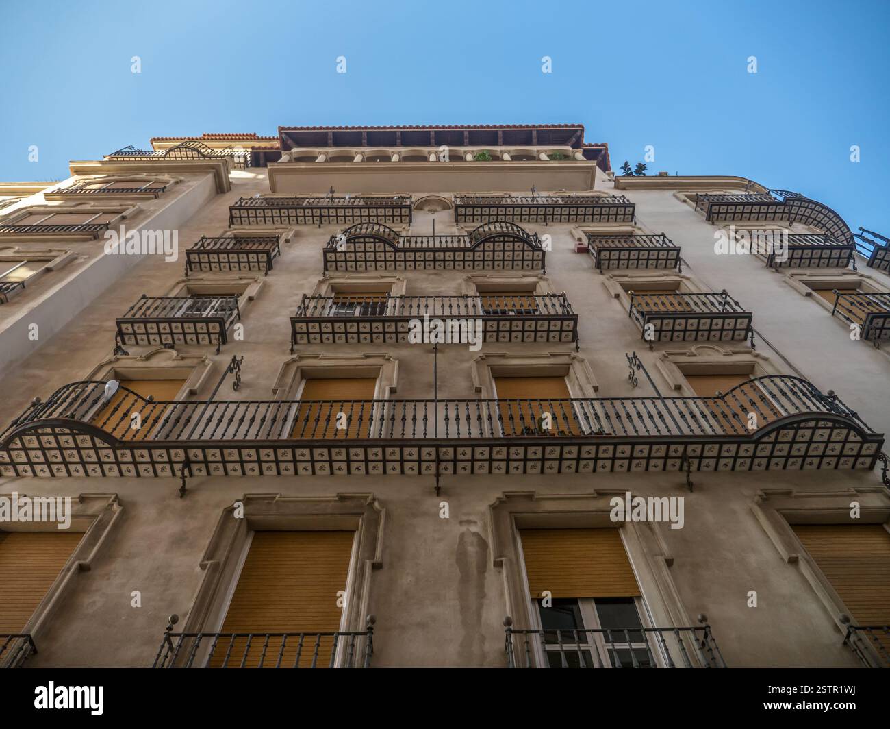 Ein flacher Blick nach oben auf ein Wohngebäude mit mehreren dekorativen Balkonen vor einem klaren blauen Himmel, der die Schönheit der städtischen Architektur zum Ausdruck bringt Stockfoto