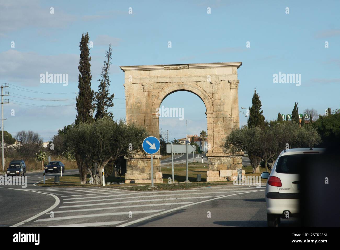 Arc de Berа in einer natürlichen Umgebung mit Bäumen. Römische Architektur, Landschaft, historisches Denkmal, architektonisches Wahrzeichen, Straße, Autos und Bewegung Stockfoto