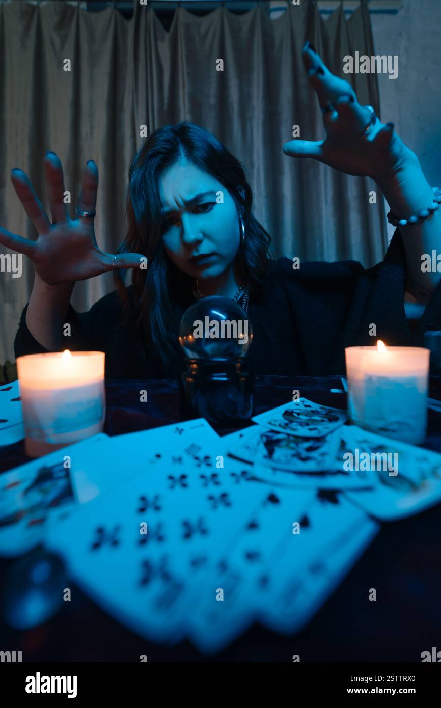 Frau Wahrsagerin errät das Schicksal der Nacht am Tisch mit Kerzen Stockfoto