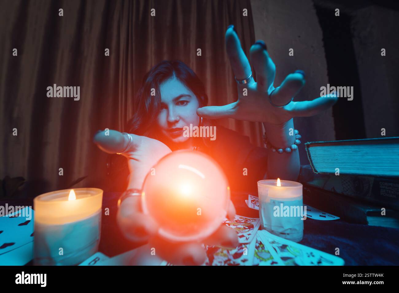 Frau Wahrsagerin errät das Schicksal der Nacht am Tisch mit Kerzen Stockfoto